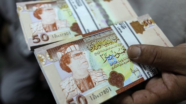 A banker shows 50 Libyan Dinar bank notes bearing the image of ousted leader Moamer Gadaffi A banker shows 50 Libyan Dinar bank notes bearing the image of ousted leader Moamer Gadaffi