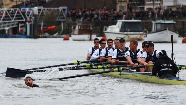 The Oxford crew look on as a man swims in the water and disrupts the Xchanging University Boat Race
