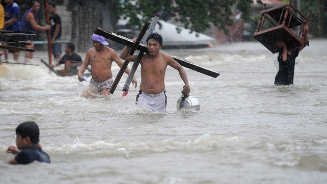 Residents carry their belongings as they wade through flood waters after a river overflowed following torrential