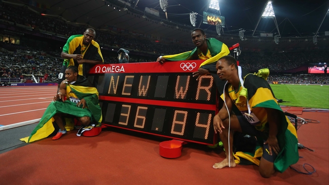 Usain Bolt, Yohan Blake, Michael Frater and Nesta Carter of Jamaica celebrate next to the clock after winning gold and setting a new world record of 36.84