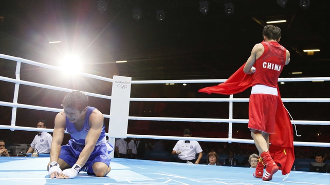 Kaeo Pongprayoon of Thailand falls to his knees as Shiming Zou of China holds the Chinese national flag after being declared winner