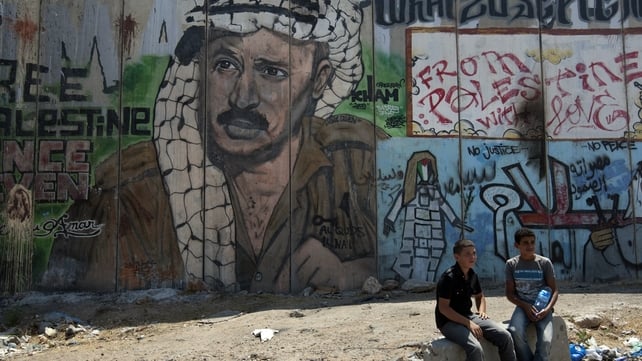 Palestinian boys sit next to a mural of late Palestinian leader Yasser Arafat Palestinian boys sit next to a mural of late Palestinian leader Yasser Arafat