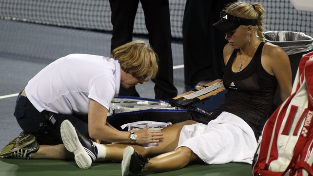 Caroline Wozniacki gets some medical attention during her opening round defeat to Romania's Irina-Camelia Begu