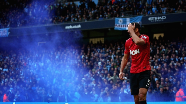 Rio Ferdinand reacts after being struck by an object thrown from the crowd