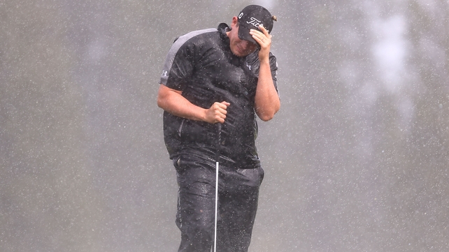 Scott Stallings shields himself from the wind and rain during the opening round