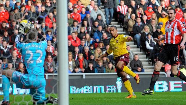 John O'Shea looks on as Arsenal's Theo Walcott (c) sees his shot saved by Simon Mignolet