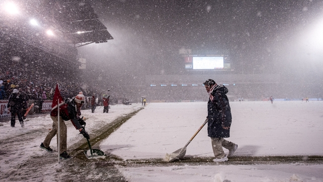 Event staff clear snow near the corner of the field even as play continues in the snow during a FIFA 2014 World Cup Qualifier match between Costa Rica and United States