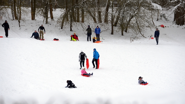 Adults and children play in the snow in Ruthing, North Wales