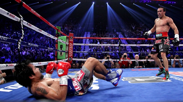 Manny Pacquiao (L) falls to the canvas after being knocked down by Juan Manuel Marquez
