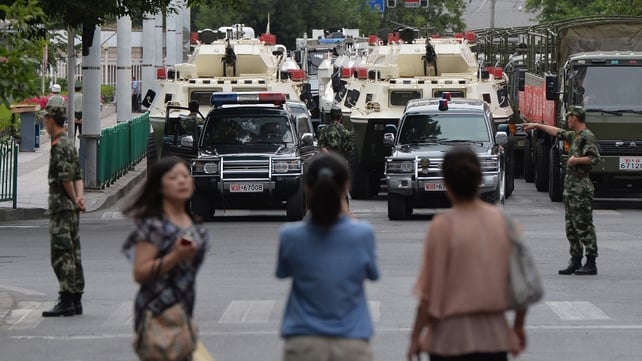 People watch as paramilitary police prepare to ride in armoured vehicles during a "show of force" ceremony in Urumqi, following after a series of attacks in Xinjiang Province People watch as paramilitary police prepare to ride in armoured vehicles during a "show of force" ceremony in Urumqi, following after a series of attacks in Xinjiang Province