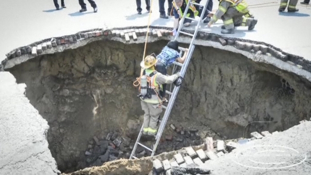 Fire crews helped the driver out of the sinkhole before she was taken to hospital Fire crews helped the driver out of the sinkhole before she was taken to hospital