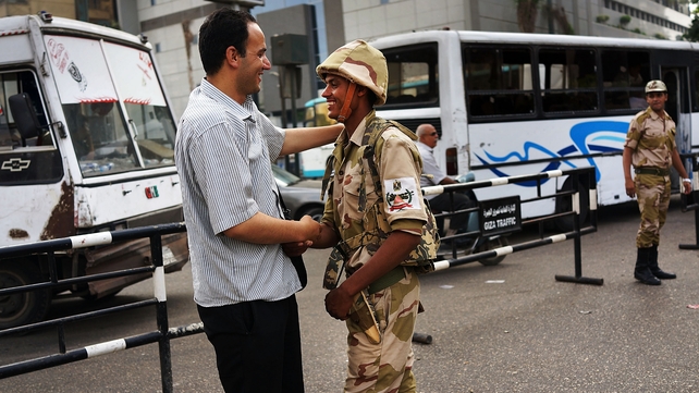 A member of the Egyptian military is greeted in support by a pedestrian in the district of Giza