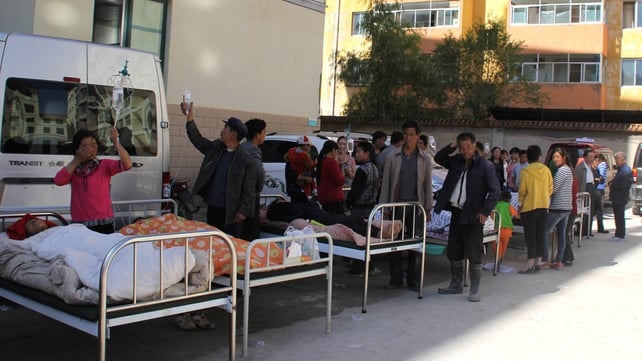 Injured people are treated on beds outside a hospital in Minxian County