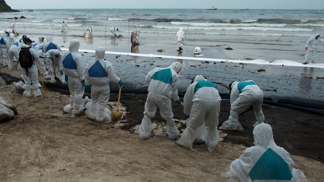 Soldiers and volunteers work to clear sludge off the white sand beach in Koh Samet Soldiers and volunteers work to clear sludge off the white sand beach in Koh Samet