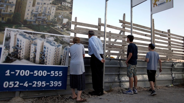 Israelis stand next to a sales promotion sign for a new Jewish neighbourhood in east Jerusalem Israelis stand next to a sales promotion sign for a new Jewish neighbourhood in east Jerusalem