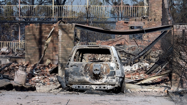 A burnt out car sits at the front of a house destroyed by bushfires in Winmalee in Sydney's Blue Mountains