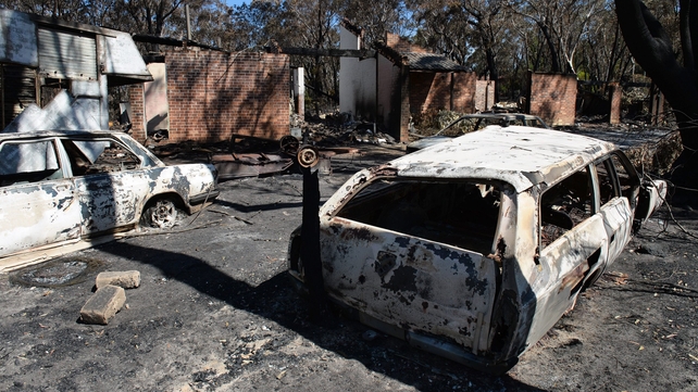 Burnt out cars sit in front of a destroyed house at Mount Victoria