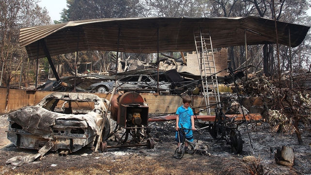 Lyndon Dunlop inspects the remains of his grandparents' home of 41 years, which was destroyed by the bushfire in Winmalee