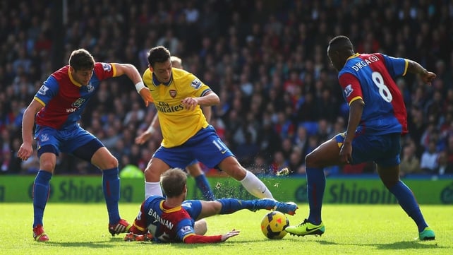 Mesut Oezil of Arsenal is challenged by Barry Bannan (c), Joel Ward (l) and Kagisho Dikgacoi of Crystal Palace