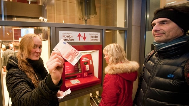 A woman shows a €10 note after withdrawing it from a cash machine in Riga A woman shows a €10 note after withdrawing it from a cash machine in Riga