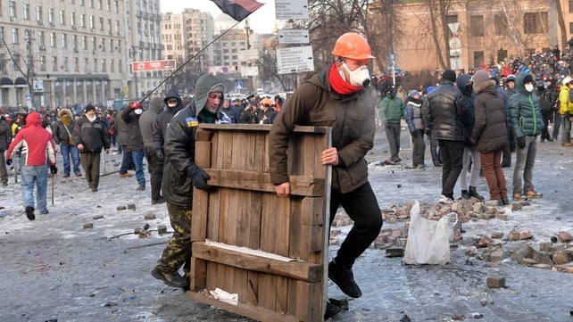 Protesters carry a wooden board to build barricades during clashes with the police in Kiev Protesters carry a wooden board to build barricades during clashes with the police in Kiev