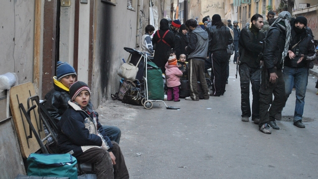 Syrians gather with their belongings in a street of a besieged district of the central city of Homs Syrians gather with their belongings in a street of a besieged district of the central city of Homs