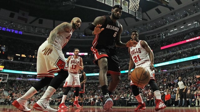 Carlos Boozer (l) and Jimmy Butler of the Chicago Bulls watch as LeBron James of the Miami Heat looses the ball out of bounds