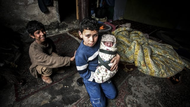 A Syrian refugee boy poses with his newborn brother as their mother lies near them in a house in the Basaksehir district of Istanbul A Syrian refugee boy poses with his newborn brother as their mother lies near them in a house in the Basaksehir district of Istanbul