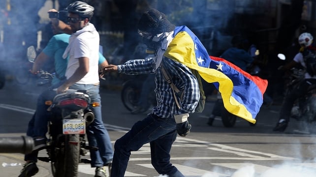 An opponent of Venezuelan President Nicolas Maduro returns a tear gas cannister during a protest in Caracas An opponent of Venezuelan President Nicolas Maduro returns a tear gas cannister during a protest in Caracas