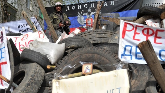 A pro-Russia activist stands guard in front of a flag of the so-called Donetsk republic A pro-Russia activist stands guard in front of a flag of the so-called Donetsk republic