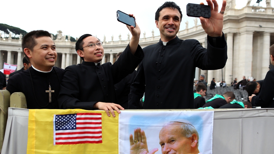Priests gathered in St Peter's Square take selfies