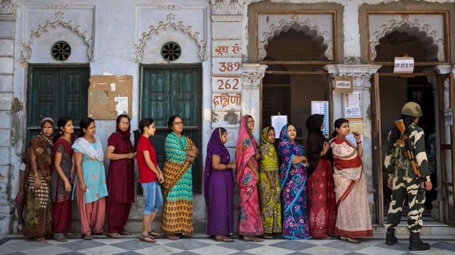 A border police officer stands guard as Indians wait in line to vote at a polling station in Varanasi A border police officer stands guard as Indians wait in line to vote at a polling station in Varanasi