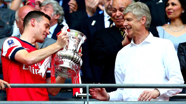 Thomas Vermaelen passes the trophy to Arsene Wenger