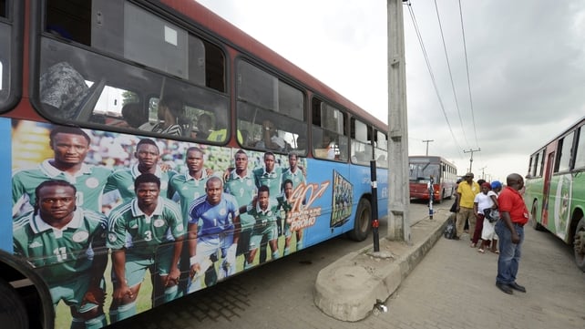 Commuters queue to board a bus in Lagos decorated with photographs showing 'Super Eagles' players Commuters queue to board a bus in Lagos decorated with photographs showing 'Super Eagles' players