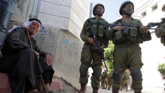 An elderly Palestinian man sits near Israeli soldiers taking part in a search operation for three Israeli teenagers An elderly Palestinian man sits near Israeli soldiers taking part in a search operation for three Israeli teenagers