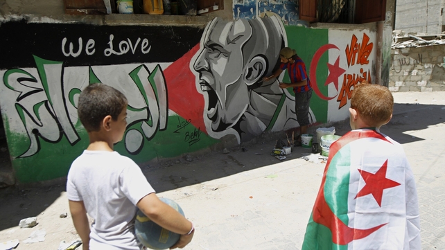 Palestinian boys, one weraing an Algerian flag, looks at graffiti-artist, Belal Khaled painting a portrait Italian football player Andrea Pirlo in Gaza Palestinian boys, one weraing an Algerian flag, looks at graffiti-artist, Belal Khaled painting a portrait Italian football player Andrea Pirlo in Gaza