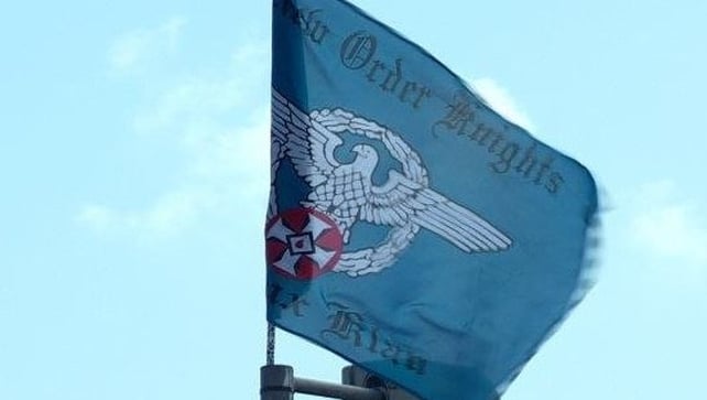 The flag features an Aryan eagle and red KKK symbol and bears the words New Order Knights and Ku Klux Klan The flag features an Aryan eagle and red KKK symbol and bears the words New Order Knights and Ku Klux Klan