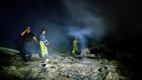Firefighters spray water to extinguish a fire at the scene of the wreckage
