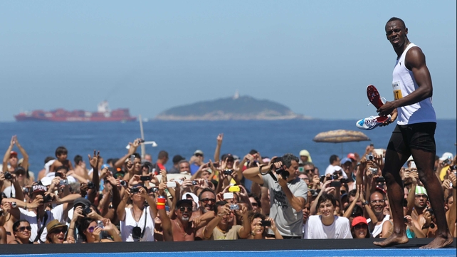 Usain Bolt prepares to throw his running shoes to the crowd after winning a 150m race on the Rio beachfront in March 2013