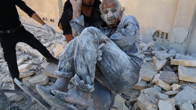 A man is rescued after a Syrian government helicopter allegedly dropped a barrel bomb on a neighbourhood in Aleppo
