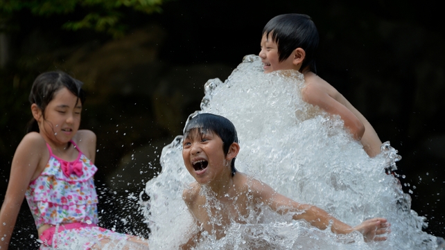 Children keep cool in a Tokyo park as Japan's heat wave continues with temperatures as high as 39C in some areas