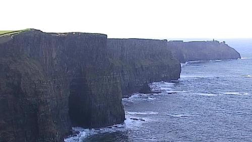 The surfer made it to shore beneath the Cliffs of Moher, which extend to 700 feet above him