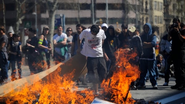 A demonstrator sets fire to a barricade during rioting as a 24-hour strike is called in Barcelona