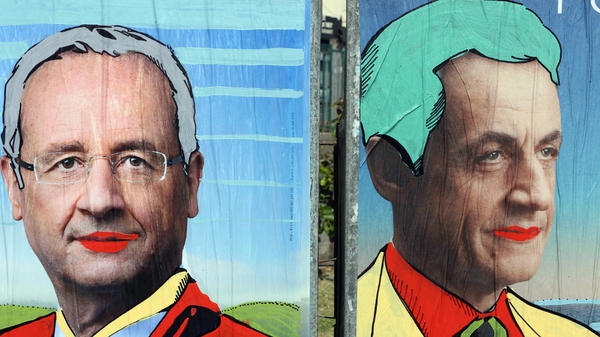 Graffiti tagged on official campaign posters of Francois Holland (L) and incumbent president Nicolas Sarkozy