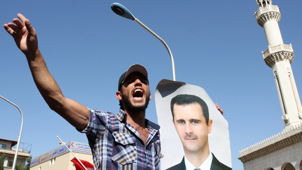 A Syrian man, holding a picture of President Bashar al-Assad shouts pro-regime slogans near the Othman Mosque in Damascus on Saturday