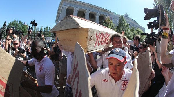 English fans carry a coffin painted with a St George's Cross and with the words 'You're wrong Campbell' painted on the side in Donetsk