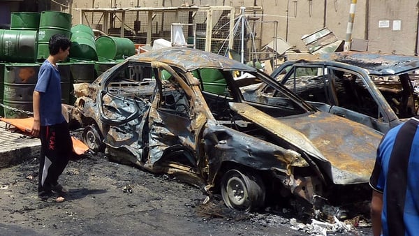 Iraqis inspect the scene of a car bomb in Sadr City