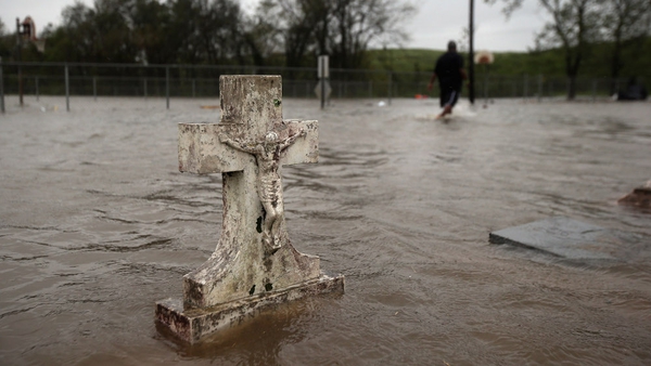 Errol Ragas walks past a flooded cemetery while recovering dry blankets from his home in Plaquemines Parish