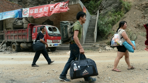 Residents walk past destroyed vehicles as they evacuate a landslide area in Yunnan Province
