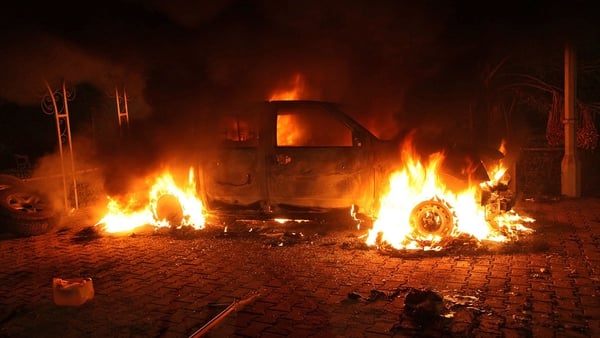 A vehicle is engulfed in flames after it was set on fire inside the consulate compound